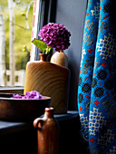 PInk hydrangeas in wooden vase on windowsill with blue curtain fabric
