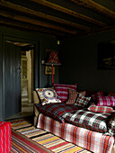 Cushions covered in assorted tartans on sofa in beamed farmhouse