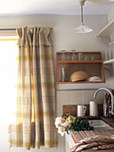 Wall mounted plate rack with tartan curtains in Scottish kitchen