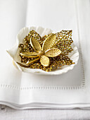 Gold leaf and flower on seashell with white table linen