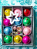 Multicoloured baubles in storage box with star shaped button decoration