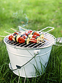 Courgette and tomato kebabs on barbecue bucket