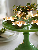 Lit tealights in stars with ivy on green cake stand