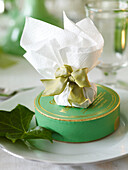 Gift wrapped in tissue with a silk bow on giftbox with ivy