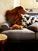 Woollen blanket and cushions on sunlit grey sofa