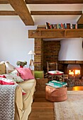 Book storage on mantelpiece above lit wood burning stove in living room of Cranbrook family home, Kent, England, UK