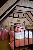Red gingham check on bed in attic conversion of timber framed cottage, Grafty Green, Kent, England, UK