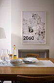 2060' artwork with crockery on polished wood table in kitchen of St Leonards home, East Sussex, England, UK