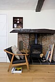 Danish 1940s style armchair at exposed brick fireside in white timber framed cottage