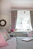 Koordinierte floral gemusterte Kissen und Vorhänge im Schlafzimmer des Cottage in Corfe Castle, Dorset, England, UK