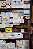 Wine bottle labels on wooden door in Sandhurst cottage, Kent, England, UK