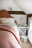 Pink quilt in attic bedroom of Egerton cottage, Kent, England, UK