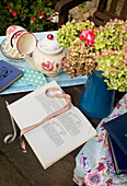Handschrift in Tagebuch mit Teetassen und Hortensien auf Tisch im Freien in Egerton, Kent, England, UK