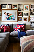 Family photographs on living room wall above grey sofa with Union Jack cushions in Smarden home Kent England UK
