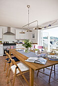 Holztisch in weißer Einbauküche mit gefliestem Boden, Dartmouth, Devon, UK
