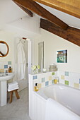 Weißes Badezimmer mit Balken und pastellfarbenen Fliesen in einem Haus in Dartmouth, Devon, Großbritannien