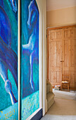 Large blue art canvas with wooden wardrobe in hallway of Etchingham farmhouse East Sussex England UK