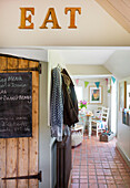 Coats hang in terracotta hallway with chalkboard in High Halden farmhouse Kent England UK