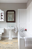 White bathroom with vintage wooden mirror above pedestal basin in Kilndown home Cranbrook Kent England UK
