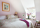 Floral quilt on double bed with dormer window in Worth Matravers cottage Dorset England UK