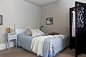 Hellblauer Bettbezug auf Bett mit schwarzem Paravent in Old Town Schlafzimmer in Portsmouth England UK