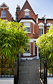 Bambus und schmiedeeisernes Geländer mit Pflastersteinen an der Backsteinfassade eines Hauses in Wandsworth, London, England UK