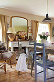 Painted chairs at dining table with gilt framed mirror in Kent home England UK