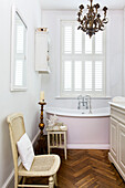 Wicker chair and freestanding bath with parquet floor in bathroom of Victorian villa Kent England UK