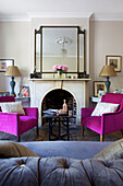 Grey upholstered sofa with pink armchairs in living room of Hackney home London England UK