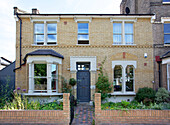 Blaugraue Eingangstür und Backsteinfassade eines Hauses in Hackney, London, England, Vereinigtes Königreich