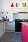 Kettle on range oven with pink kitchen island and flagstone floor in Woodchurch home Kent England UK