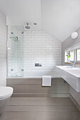 White tiled bathroom with shower screen and double basin in Rye home East Sussex UK