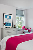 PInk runner on double bed with framed book cover on chest in Dartmouth Devon UK