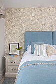 Hellblaues Bett mit gemusterter Tapete im Schlafzimmer in Dartmouth, Devon, Großbritannien