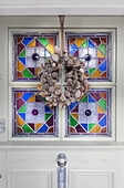 Frosted wreath on front door with contemporary stained glass London UK