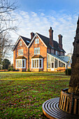 Sunlit exterior of Warehorne rectory built in 1829 with tree bench and lawn Kent UK