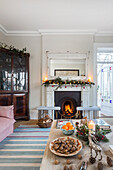 Lit fire and glass fronted cabinet with Christmas decorations in Warehorne rectory Kent UK