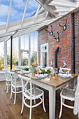 Dining table with chairs in 1820s Warehorne conservatory with exposed brick wall Kent UK
