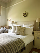 Striped blanket on bed in room with heart shaped wall hanging in Kensington home London England UK