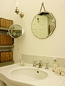 Mirrors hang above washbasin with basket storage in Kensington home London England UK