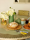 Loaf of bread and breakfast crockery on kitchen table in London home England UK