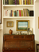 Antique writing bureau and bookshelves in living room detail of London home England UK