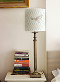 Vintage lamp with bird motif shade and books on bedside table in London home England UK