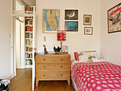 Wooden chest of drawers next to single bed in girls room with framed pictures in London home England UK