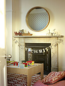 Circular mirror above fireplace with Christmas decoration in London family home England UK