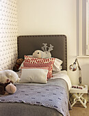 Soft toys and pillows on single bed in childs room of London family home England UK