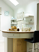 Black leather bar stool at breakfast bar with glassware on open shelves in Nottinghamshire kitchen England UK