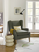 Grey armchair with side table at double doors of North London townhouse England UK