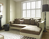 Light brown corner sofa with shuttered windows in North London townhouse England UK