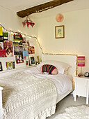 Wolldecke auf Einzelbett mit Kunstwerk und beleuchteten Lichtern in einem Haus in Nottinghamshire, England, UK